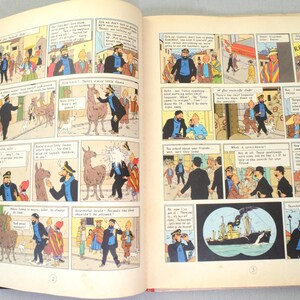 Op de afbeelding: Open boek met stripverhalen met kleurrijke illustraties. De panelen tonen personages in verschillende sc&egrave;nes, waaronder een man in een blauw jasje en een schip. De pagina's van het boek zijn cr&egrave;mekleurig.
