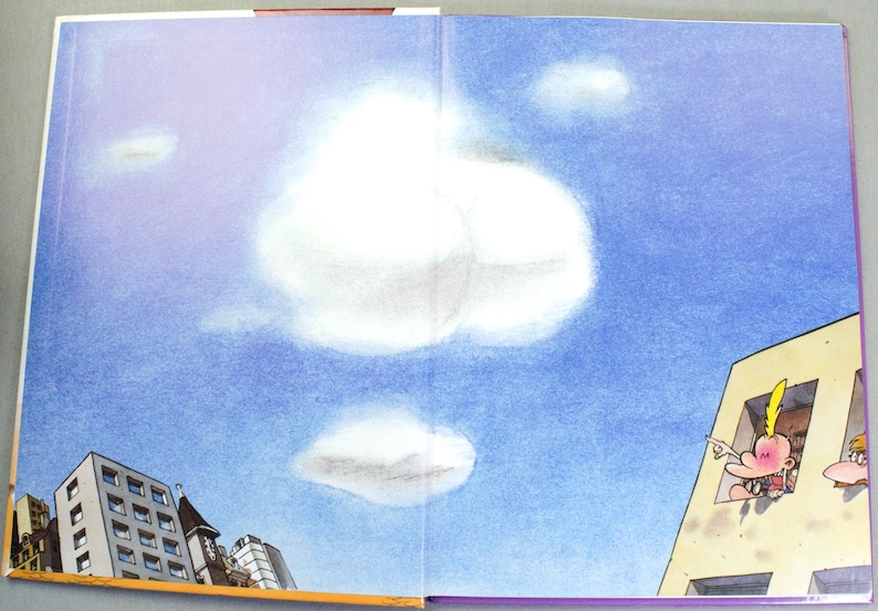 K&ouml;nnte beinhalten: Eine Buchseite mit einem blauen Himmel und wei&szlig;en Wolken. Links ist eine Ansammlung von Stadtgeb&auml;uden zu sehen. Rechts zeigt ein helles Geb&auml;ude eine Zeichentrickfigur mit gelben Haaren, die aus einem Fenster heraus in den Himmel zeigt.
