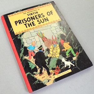 Op de afbeelding: Een vintage exemplaar van "De avonturen van Kuifje: De Zonnetempel" stripboek. De cover toont een kleurrijke illustratie van Kuifje, Kapitein Haddock en andere personages in een jungle-omgeving. Het boek heeft een gele titelbanner en een rode rug.