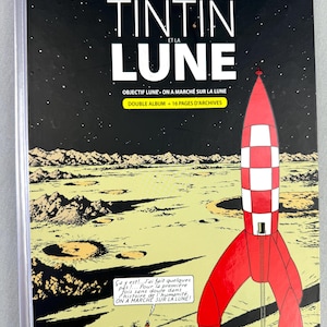 Puede incluir: Portada de c&oacute;mic con un cohete rojo y blanco sobre un paisaje lunar. El t&iacute;tulo es "TINTIN ET LA LUNE" con texto adicional. El fondo muestra un cielo estrellado y una representaci&oacute;n detallada de la superficie lunar.