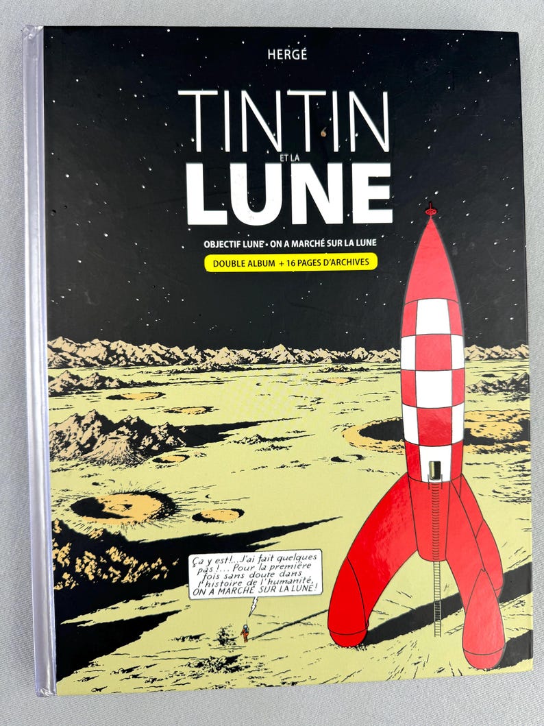 Puede incluir: Portada de c&oacute;mic con un cohete rojo y blanco sobre un paisaje lunar. El t&iacute;tulo es "TINTIN ET LA LUNE" con texto adicional. El fondo muestra un cielo estrellado y una representaci&oacute;n detallada de la superficie lunar.