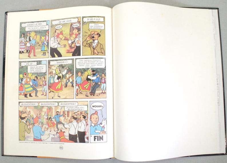 May include: Open book with comic strip panels featuring cartoon characters in a colorful setting. Text bubbles contain speech in French. The right page is blank. The word "FIN" is visible.