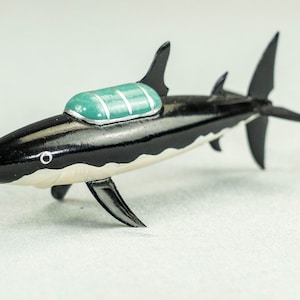Könnte beinhalten: Schwarz-weißes Spielzeug-U-Boot in Form eines Hais mit einem grün-weißen Verdeck.