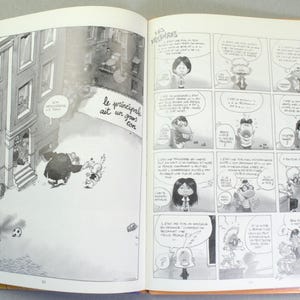 Puede incluir: Un libro abierto que muestra ilustraciones en blanco y negro en ambas p&aacute;ginas. La p&aacute;gina izquierda presenta un gran dibujo de un edificio y personajes, mientras que la derecha contiene una historieta con globos de texto y escritura en franc&eacute;s.