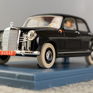 Puede incluir: Modelo de coche negro vintage con detalles cromados, neum&aacute;ticos de banda blanca y matr&iacute;cula roja. El coche est&aacute; sobre una base azul. La matr&iacute;cula dice "8264F".