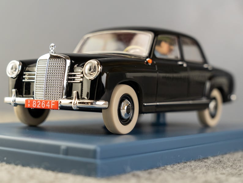 Puede incluir: Modelo de coche negro vintage con detalles cromados, neum&aacute;ticos de banda blanca y matr&iacute;cula roja. El coche est&aacute; sobre una base azul. La matr&iacute;cula dice "8264F".