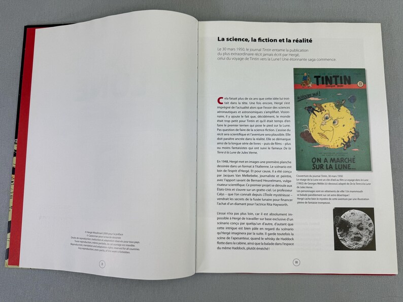 Puede incluir: Libro abierto con lomo rojo y cubierta negra. La p&aacute;gina de la derecha presenta texto en franc&eacute;s y una ilustraci&oacute;n de la portada del c&oacute;mic de Tint&iacute;n titulado "On a march&eacute; sur la Lune".