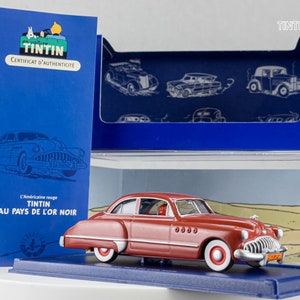 May include: A red 1940s American car model, a collectible from the Tintin series, "The Adventures of Tintin: The Red American Car". The car is in a display case with a certificate of authenticity.