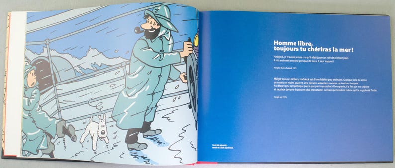 May include: A double-page spread from a comic book featuring a cartoon illustration. The left page shows a man in a blue coat and hat, holding a wheel, with a dog and another person. The right page has blue background with white text.