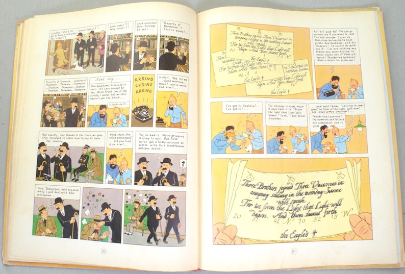 May include: Open book with comic strip panels featuring illustrations of characters in suits and hats. Text bubbles and handwritten notes are present. The comic strip has a vintage style with a yellowed background.