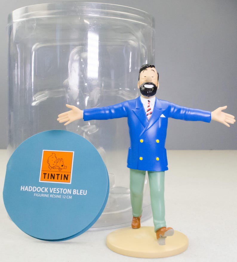 以下が含まれることがあります： タンタンシリーズのハドック船長のフィギュア。 金色のボタンが付いた青いブレザー、緑色のズボン、茶色の靴を履いています。 フィギュアの高さは約12cmで、ベージュ色の台座の上に立っています。 タンタンのロゴが入った青い丸いタグも付いています。