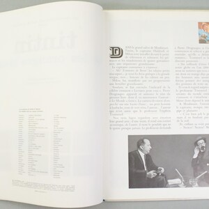 Puede incluir: Libro abierto con texto e ilustraciones. La p&aacute;gina izquierda tiene una lista de palabras. La p&aacute;gina derecha tiene texto y dos peque&ntilde;as fotos en blanco y negro de hombres. El libro est&aacute; abierto sobre una superficie blanca.