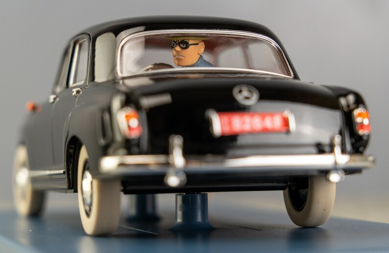 Puede incluir: Un modelo de coche Mercedes-Benz negro vintage con neum&aacute;ticos de banda blanca. El coche tiene una matr&iacute;cula roja y una figura de un conductor con gafas. Un coche cl&aacute;sico de colecci&oacute;n.