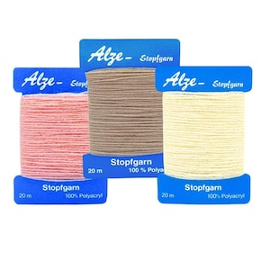 May include: Three spools of Alze Stopfgarn thread in peach, tan, and cream. Each spool is labelled with the brand name, thread type, and fibre content. The thread is 20 metres long and made of 100% Polyacryl.