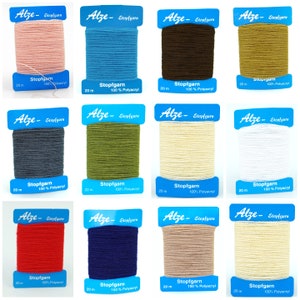May include: Twelve spools of Stopfgarn 100% Polyacryl yarn in a variety of colours, including pink, blue, brown, gold, grey, green, beige, white, red, navy, and light brown. Each spool is labelled with the brand name "Alze" and the length of the yarn, 20 metres.