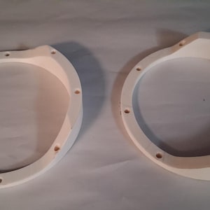 May include: Two off-white, circular wooden frames with multiple evenly spaced holes. The frames have a curved design and are positioned side by side on a light-colored surface. The frames appear to be new.