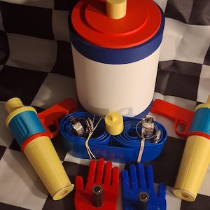 Puede incluir: Colección de juguetes vintage coloridos, que incluyen un recipiente rojo, blanco y azul con tapa amarilla, dos pistolas de juguete amarillas y azules y juguetes con forma de mano rojos y azules. Dispuestos sobre una superficie a cuadros en blanco y negro.