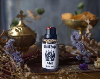 Può includere: Una piccola bottiglia di vetro scuro con un tappo nero e un'etichetta bianca. L'etichetta presenta un'illustrazione in bianco e nero di una donna con corna e ali. Il testo sull'etichetta recita "Mirall Bajo Lilith Ritual Oil".