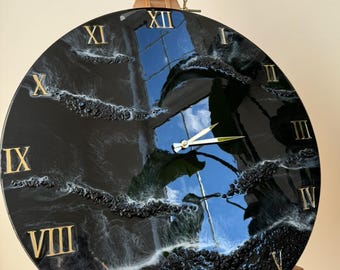 Peut inclure: Horloge en résine noire et blanche avec des chiffres romains dorés. Le cadran de l'horloge présente un design abstrait tourbillonnant avec de la résine blanche et noire.