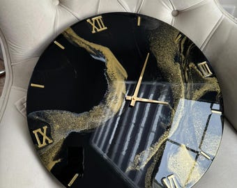 May include: Black and gold resin clock with Roman numeral markings. The clock face has a marbled design with gold glitter.