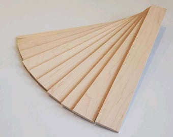 May include: A fan-shaped arrangement of light-colored wooden planks. The planks are rectangular and appear to be made of unfinished wood. The arrangement suggests a potential for decorative or construction use.