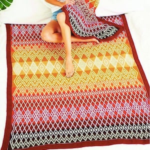 May include: A red, orange and yellow geometric patterned throw blanket with a white diamond pattern. The blanket is folded and draped over a bed.