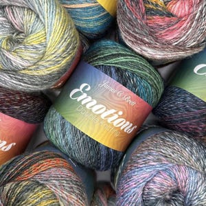 May include: A collection of James C. Brett Emotions double knitting yarn balls. Each ball features a variegated blend of colours including green, blue, grey, pink, and yellow. The central label displays the text James C. Brett Emotions Double Knitting.