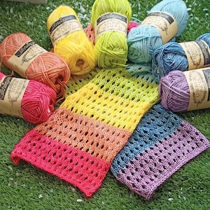 Może przedstawiać: Różnokolorowy szal wykonany na szydełku z przędzy w różnych kolorach. Przędza jest oznaczona jako "Scheepjes Stone Washed" i występuje w różnych kolorach, w tym żółtym, zielonym, niebieskim, fioletowym i różowym.