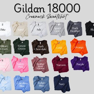 May include: A Gildan 18000 crewneck sweatshirt color chart featuring nineteen folded long-sleeve shirts in various colors including white, sand, ash, sport gray, dark heather, black, military green, forest green, dark chocolate, gold, orange, light pink, safety pink, heather sport maroon, maroon, purple, light blue, carolina blue, indigo blue, and navy.