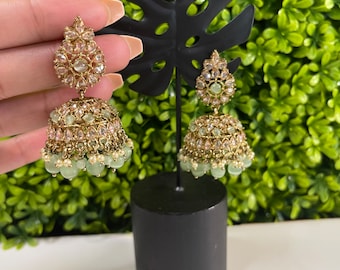 May include: A pair of gold earrings with green and pink stones. The earrings are dangling and have a bell-shaped design.