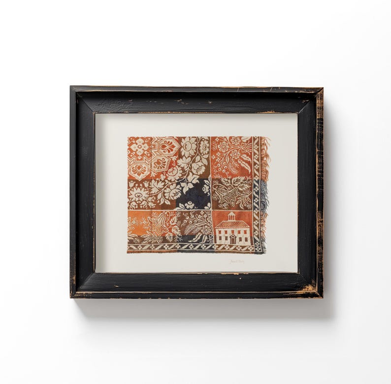 May include: Framed artwork featuring a patchwork design with floral and architectural motifs in shades of orange, white, brown, and navy blue. The artwork is encased in a distressed black wooden frame, creating a vintage aesthetic.