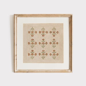 Può includere: Opera d'arte incorniciata con un motivo floreale ripetuto in rosso e verde su sfondo beige. L'opera è racchiusa in una cornice di legno colorata, creando un'estetica vintage. Il design floreale è simmetrico e dettagliato.