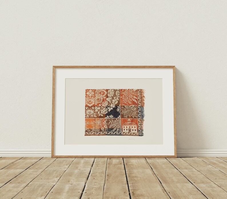 May include: Framed artwork featuring a patchwork design with floral and architectural patterns in shades of red, orange, and navy blue. The artwork is displayed in a natural wood frame, adding a touch of warmth to the piece. The artwork is displayed on a wooden floor.