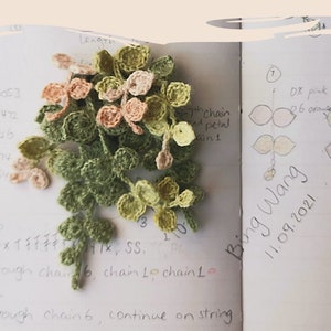 Puede incluir: Primer plano de una cadena de níqueles de ganchillo, un tipo de flor, con hojas verdes, rosas y amarillas. La imagen incluye el texto "FLORALCROCHET.COM string of nickels" y "Bing Wang 11.09.2021".