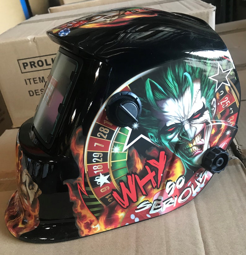 May include: Black welding helmet with a graphic of a green and red joker face with a roulette wheel and the text "Why so serious".