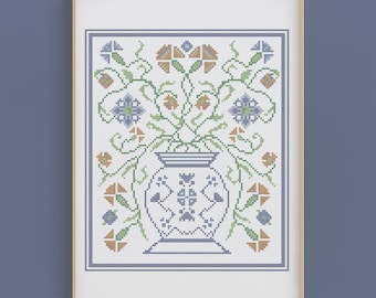 May include: A cross-stitch pattern of a blue and white vase with green and orange flowers. The vase is surrounded by a border of blue and white.