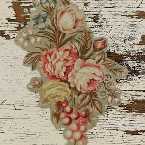 May include: A floral design featuring a bouquet of pink, red, and yellow flowers with green leaves and a cluster of red grapes. The design is set against a distressed white and brown wooden background.