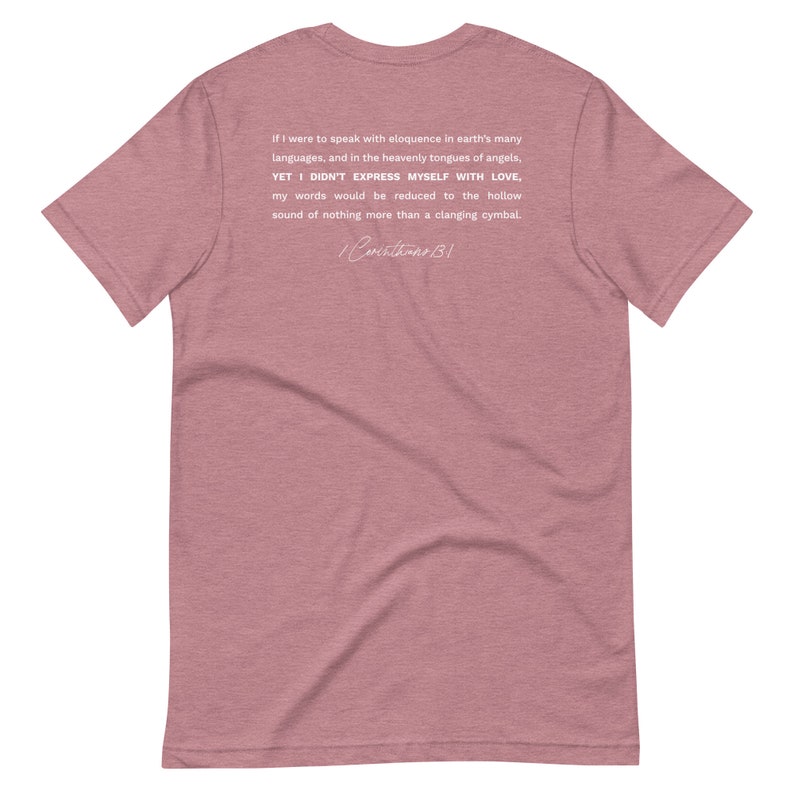 May include: A dusty rose t-shirt with white text on the back. The text reads, "If I were to speak with eloquence in earth's many languages...YET I DIDN'T EXPRESS MYSELF WITH LOVE...1 Corinthians 13:1."