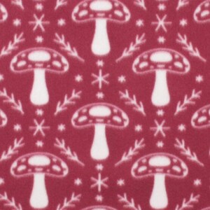 May include: A red fabric with a white repeating pattern of mushrooms and stylized branches. The mushrooms have a rounded top and a stem.