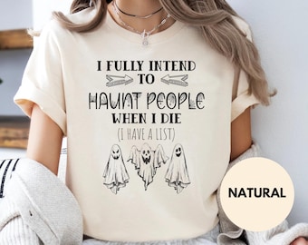 May include: A natural-colored short-sleeve t-shirt featuring black text that reads I FULLY INTEND TO HAUNT PEOPLE WHEN I DIE (I HAVE A LIST) with two arrows and three illustrated ghosts with varying facial expressions printed on the front.