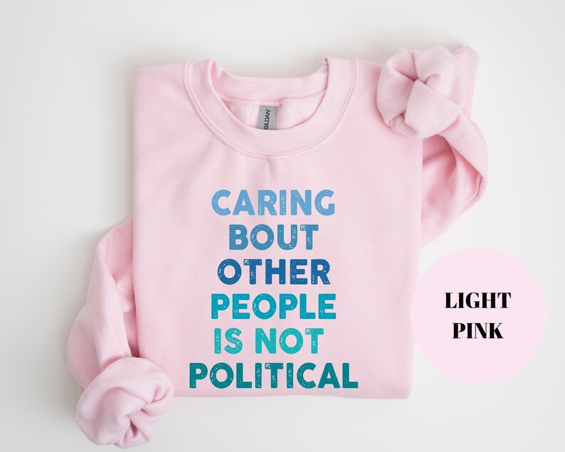 Bold statement sweatshirt with the phrase Caring About Other People Is Not Political, promoting kindness, activism, and human rights.