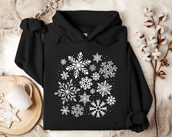 May include: Black hooded sweatshirt with a white snowflake design. The snowflakes are arranged in a cluster on the front of the sweatshirt.