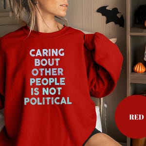 Bold statement sweatshirt with the phrase Caring About Other People Is Not Political, promoting kindness, activism, and human rights.