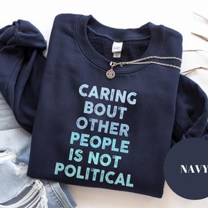 Bold statement sweatshirt with the phrase Caring About Other People Is Not Political, promoting kindness, activism, and human rights.