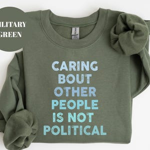 Bold statement sweatshirt with the phrase Caring About Other People Is Not Political, promoting kindness, activism, and human rights.