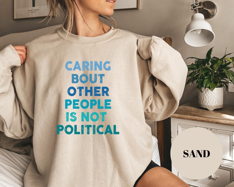 Bold statement sweatshirt with the phrase Caring About Other People Is Not Political, promoting kindness, activism, and human rights.