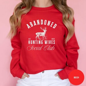A sweatshirt and shirt featuring the Abandoned Hunting Wives Social Club design with a vintage deer illustration and bold rustic lettering, perfect for hunting wives, fall season wear, hunting camp gatherings, and cozy casual outfits.