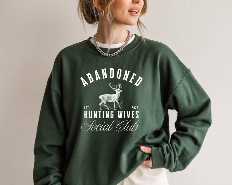 A sweatshirt and shirt featuring the Abandoned Hunting Wives Social Club design with a vintage deer illustration and bold rustic lettering, perfect for hunting wives, fall season wear, hunting camp gatherings, and cozy casual outfits.