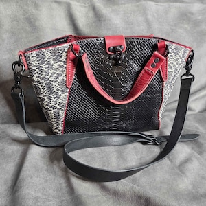 May include: A black and red handbag with a snakeskin texture and a patterned side panel. The bag has a top handle and a detachable shoulder strap. The hardware is black.