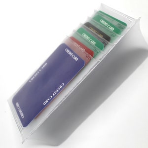 Könnte beinhalten: Ein durchsichtiger Kartenhalter aus Plastik mit sechs Fächern für Kreditkarten. Der Halter ist mit fünf Kreditkarten gefüllt, auf denen jeweils der Text "CREDIT CARD" aufgedruckt ist. Die Karten sind in verschiedenen Farben, darunter Blau, Rot, Grün und Schwarz.